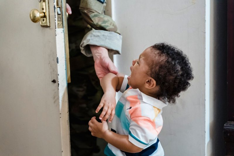 A young child cries as a soldier parent departs, highlighting a poignant family moment.