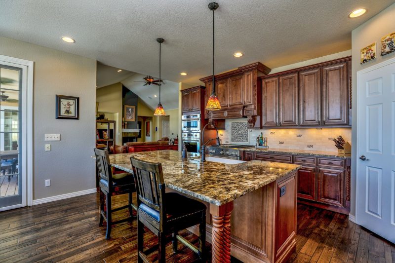 Home 17 Stylish kitchen with a granite island, wooden cabinets, and modern appliances, blending rustic and contemporary design.