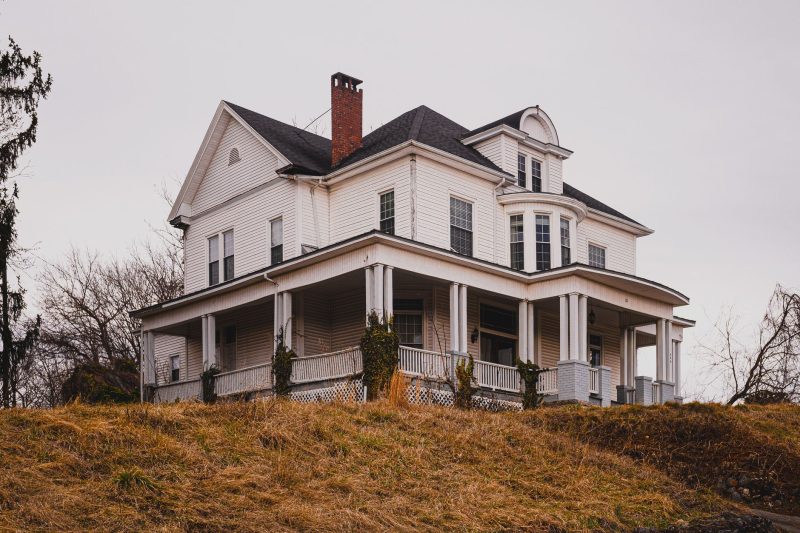 Home 14 Historic white house with a wraparound porch surrounded by colorful autumn foliage.
